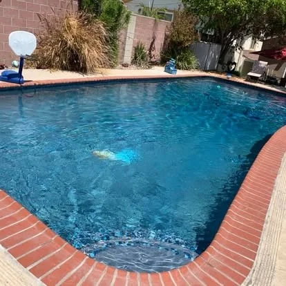 Blue pool water beside waterline tile and brick coping