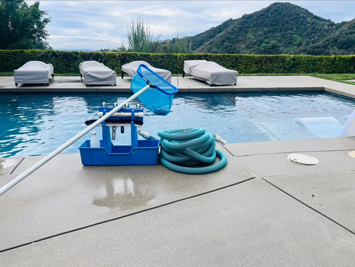 Pool cleaning equipment and hoses on the deck beside a pool