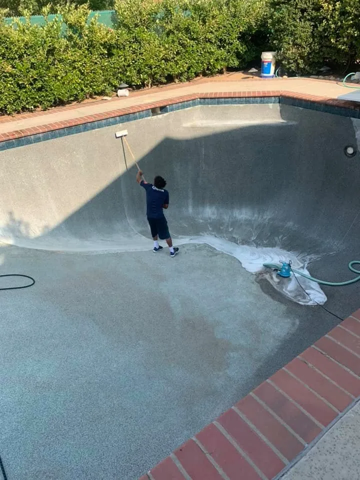 Drained pool being washed by a technician