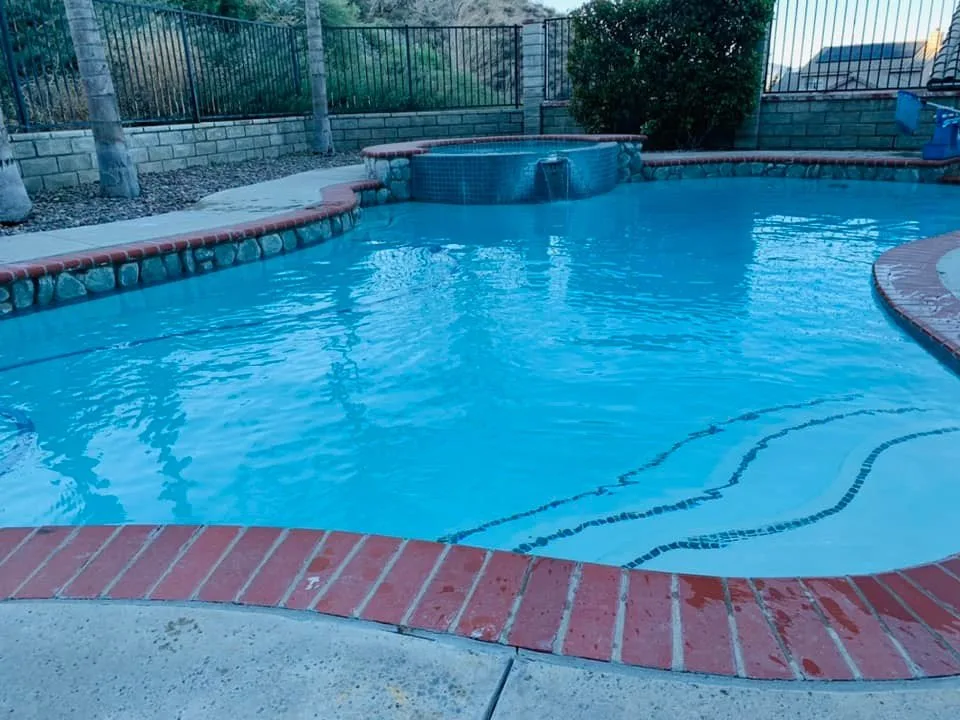 Blue pool with brick coping and a raised spa