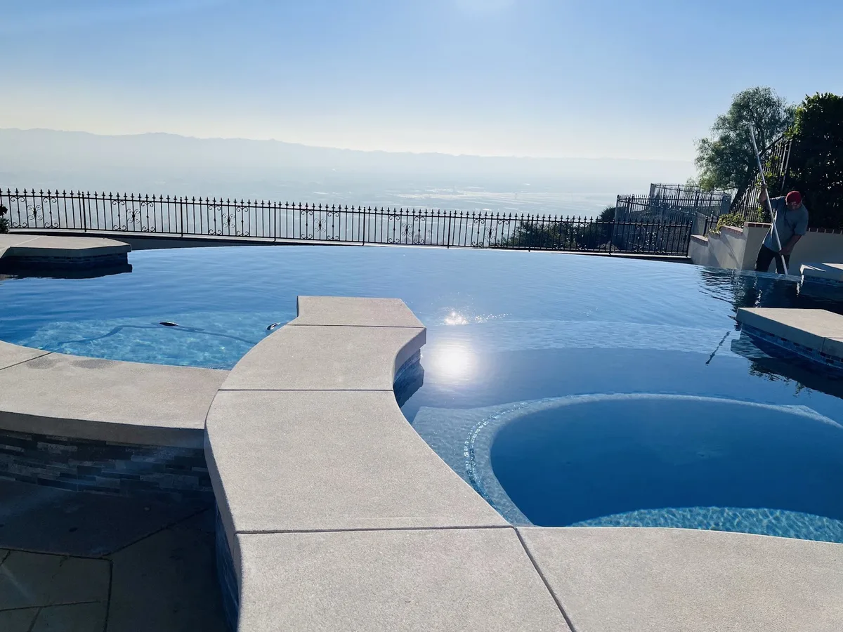 Pool and raised spa with a hillside view