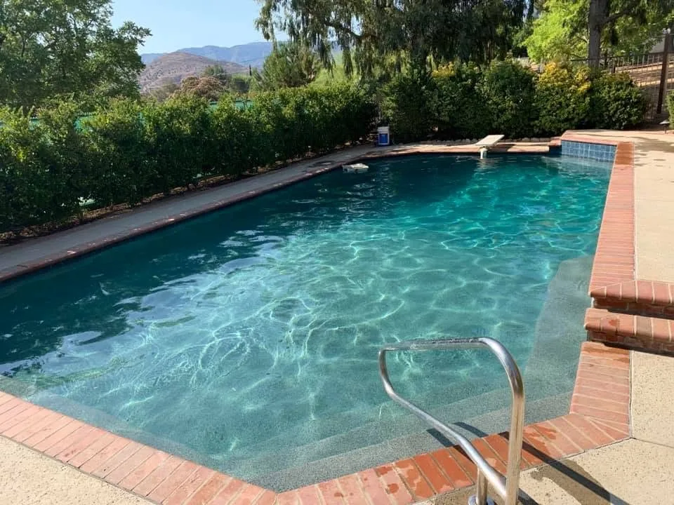 Pool with green-tinted water and an entry rail