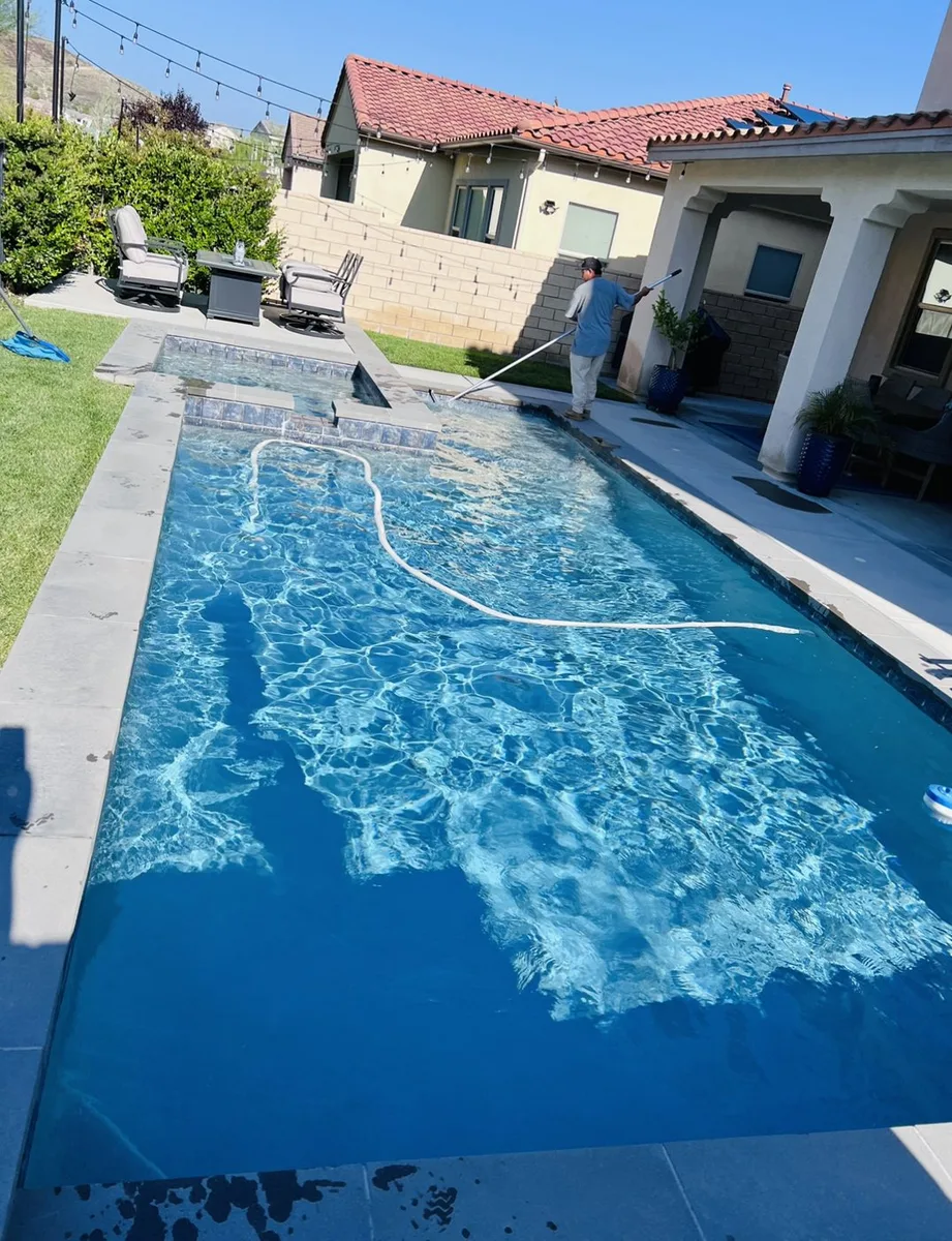 Pool surface being brushed beside a house